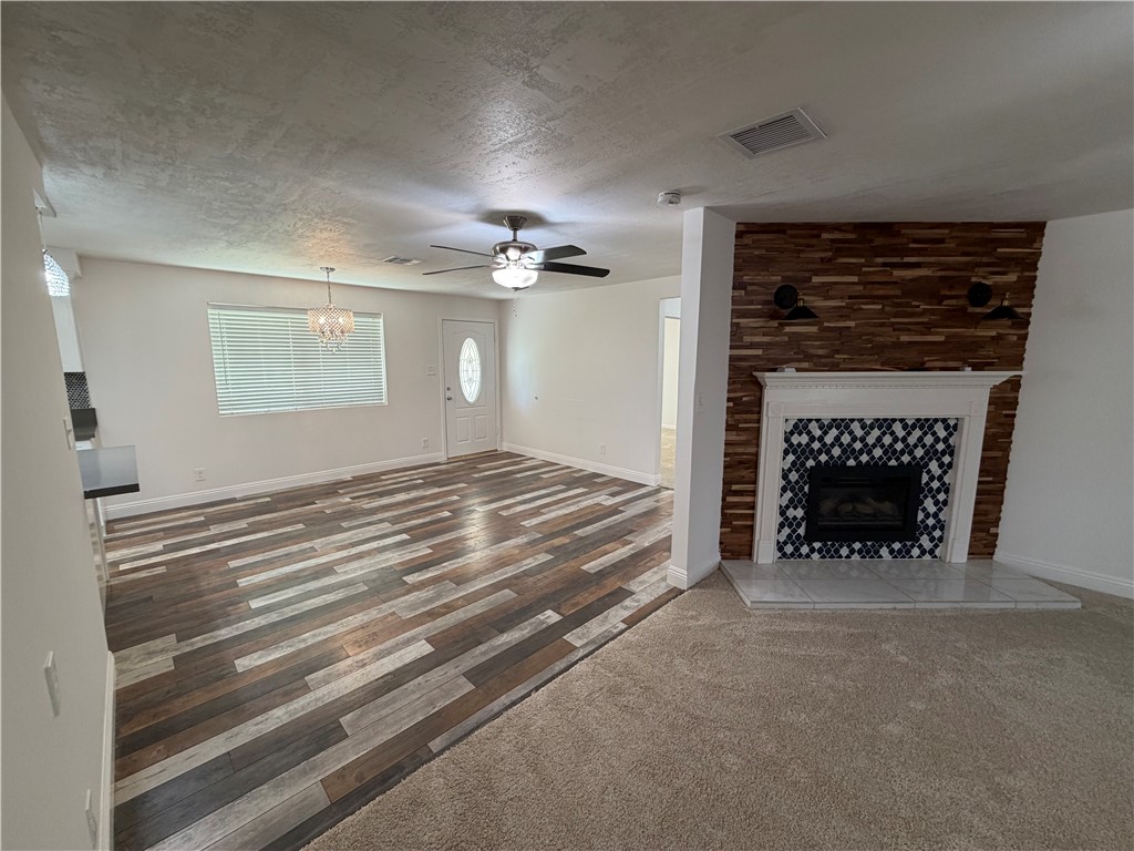 1985 Laguna Road Mohave Valley, AZ 86440 - Photo 18 of 83 Unfurnished living room featuring a tiled fireplace, a ceiling fan, a textured ceiling, dark wood finished floors, and suspended lighting