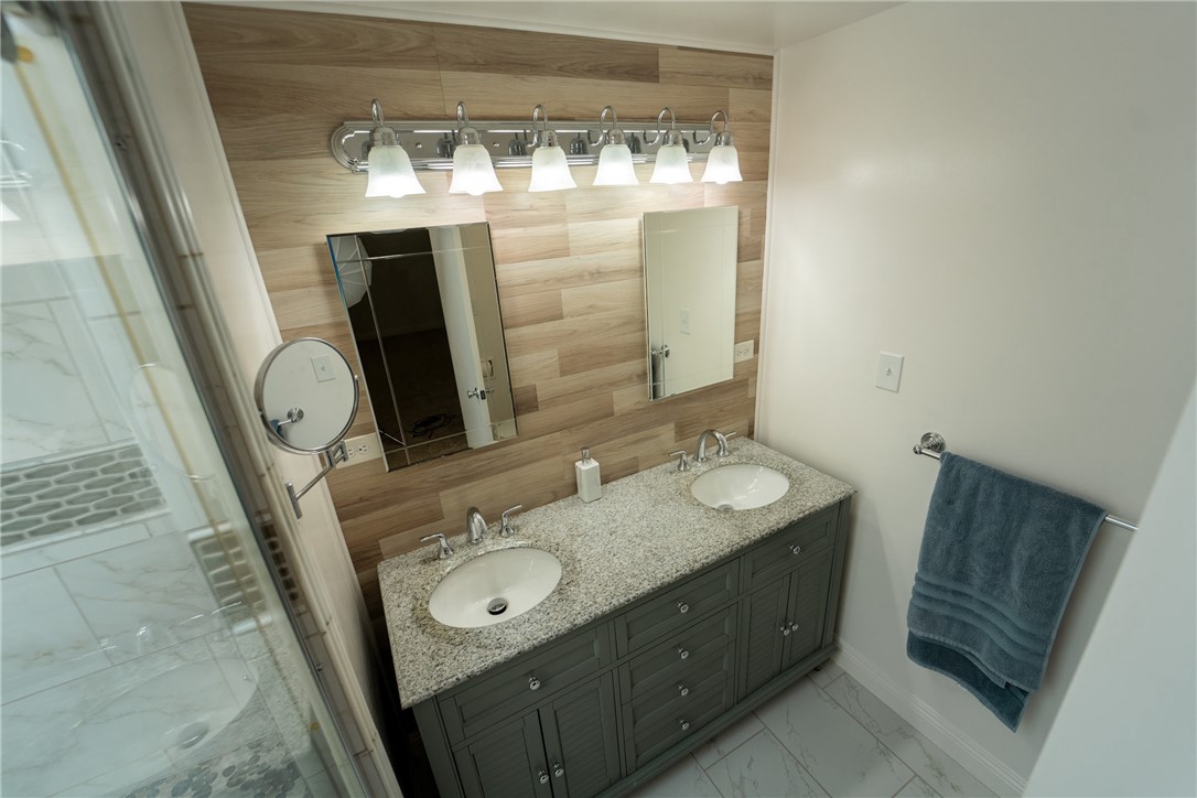 1985 Laguna Road Mohave Valley, AZ 86440 - Photo 28 of 83 Well-appointed bathroom featuring a double vanity with a granite countertop, two undermount sinks, and a stylish wood-paneled accent wall