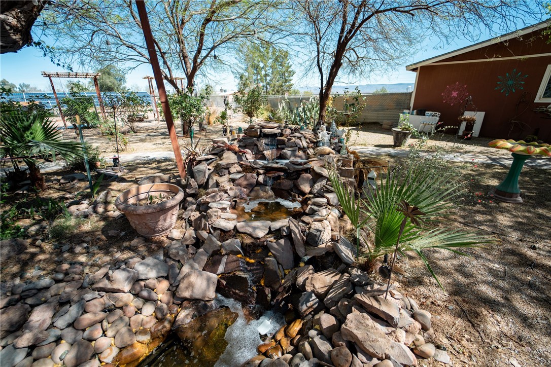 1985 Laguna Road Mohave Valley, AZ 86440 - Photo 55 of 83 The property features a rock garden with a multi-tiered waterfall, surrounded by desert landscaping and mature trees