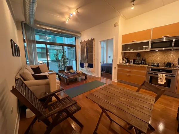 a living room with furniture a large window and stainless steel appliances