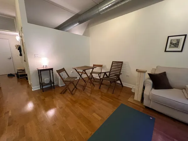 a living room with couches and kitchen view with wooden floor