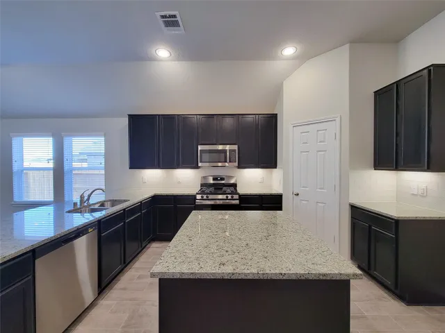a kitchen with stainless steel appliances granite countertop a sink stove and refrigerator