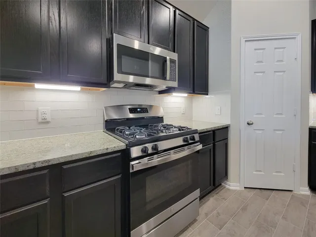a kitchen with granite countertop cabinets stainless steel appliances and wooden floor