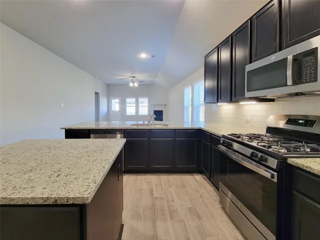 a kitchen with granite countertop stainless steel appliances and view living room