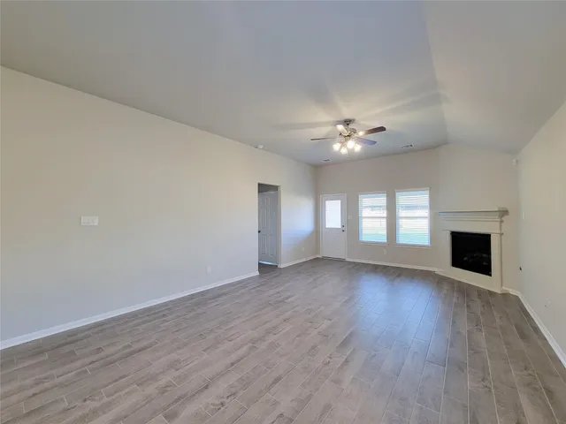 a view of an empty room with wooden floor and a fireplace