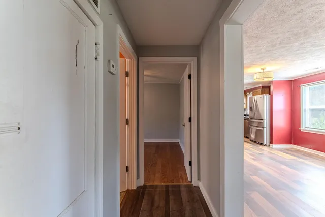 a view of a hallway with wooden floor and a bathroom