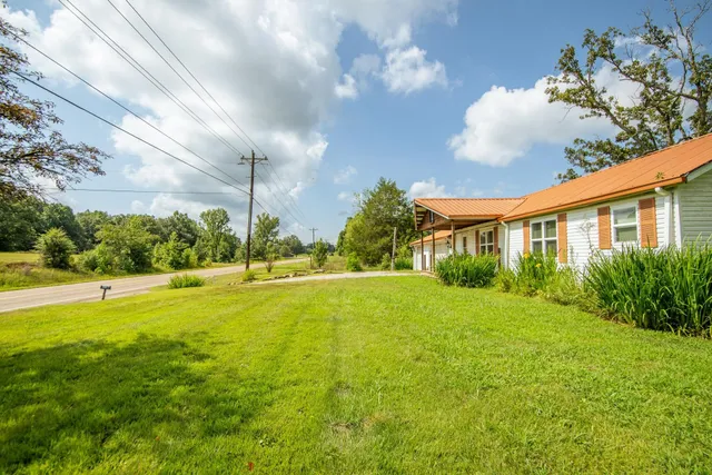 a view of an house with backyard and a tree
