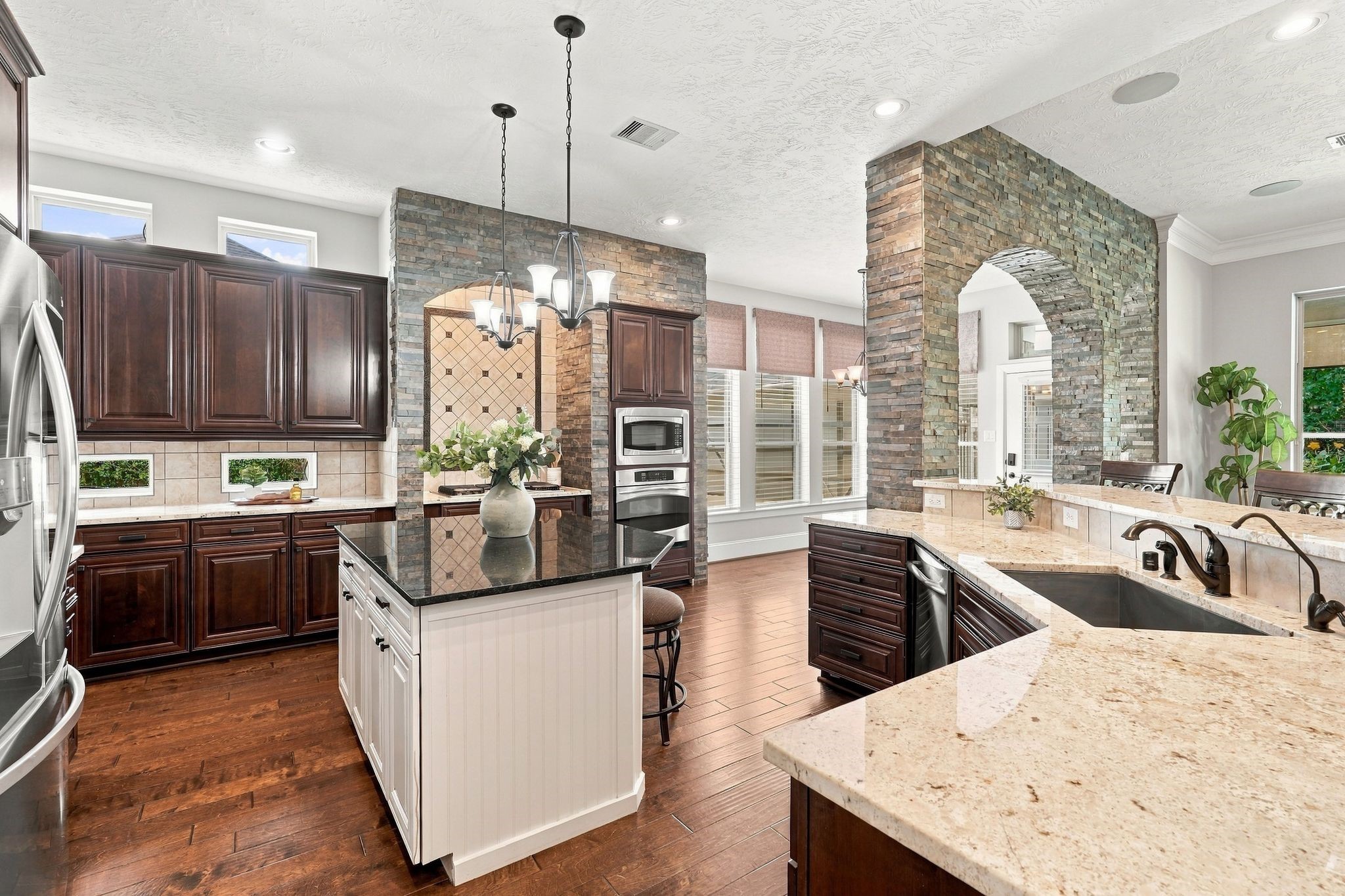 3750 Ribbon Hill Lane Spring, TX 77386 - Photo 13 of 50 Spacious kitchen featuring granite countertops, center island, stainless steel appliances, oven, microwave, abundant cabinetry and distinctive stacked stone architectural details