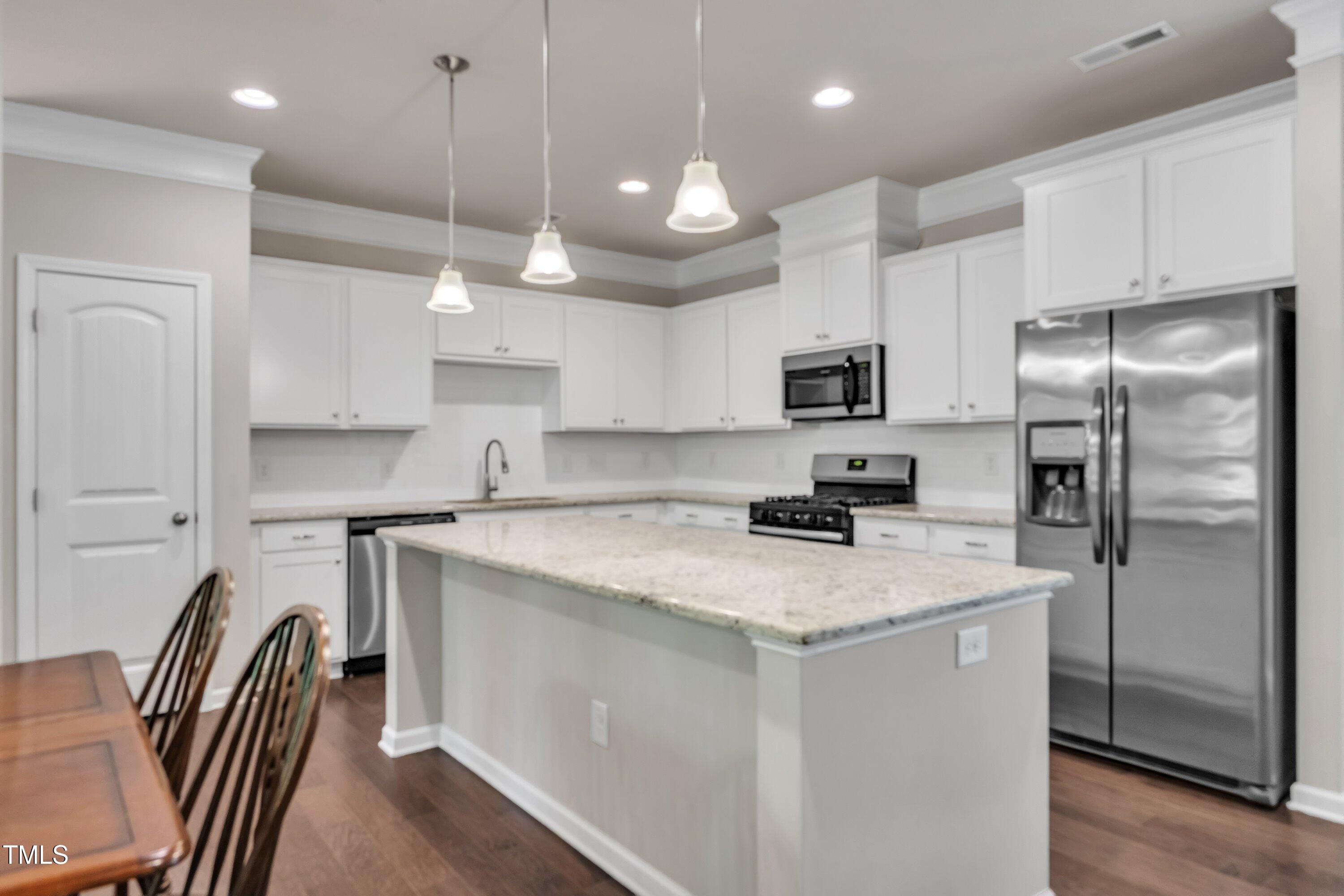 1230 Wingstem Place Raleigh, NC 27607 - Photo 12 of 41 a kitchen with stainless steel appliances granite countertop a refrigerator a stove a sink a dining table and chairs