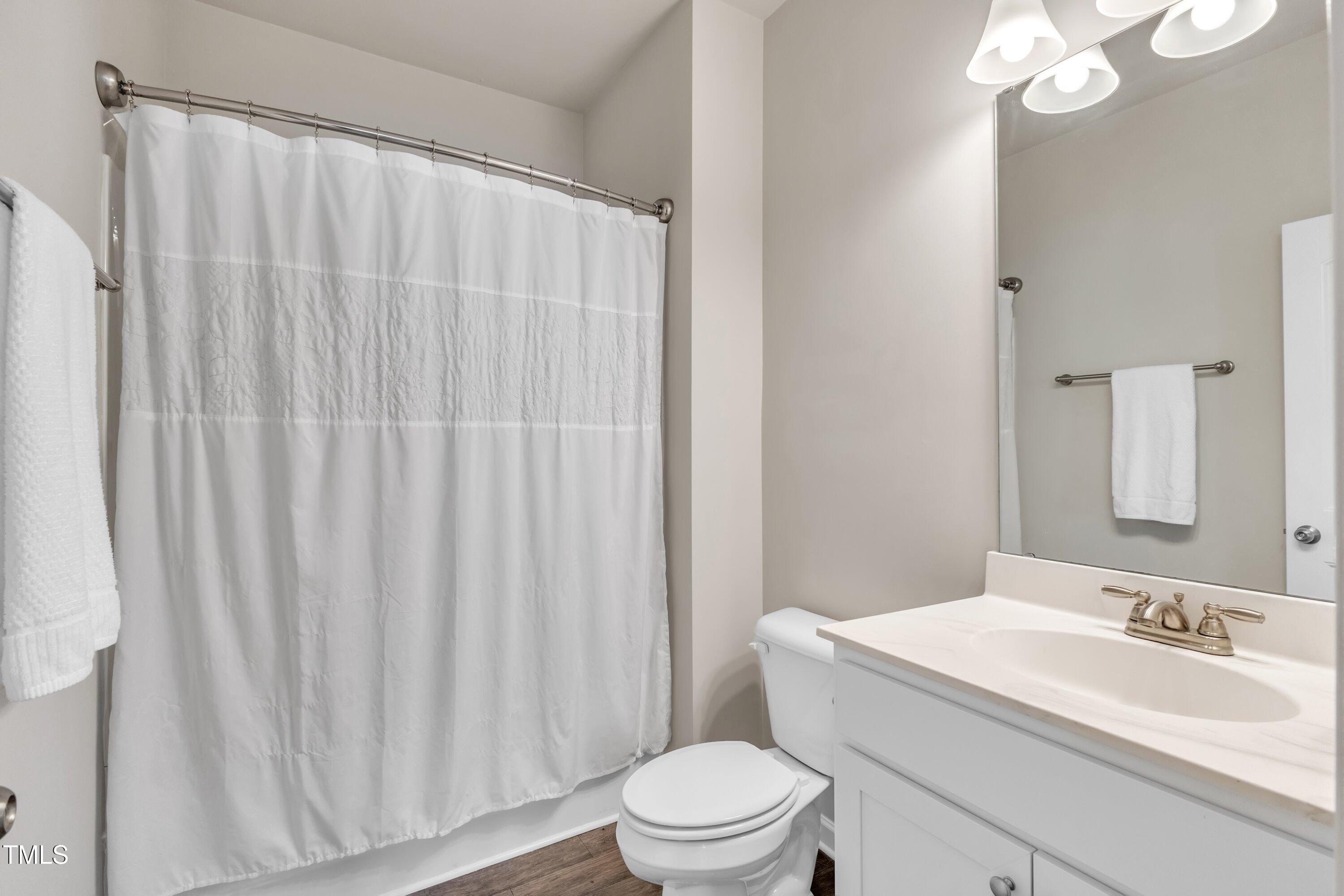 1230 Wingstem Place Raleigh, NC 27607 - Photo 32 of 41 a bathroom with a sink a toilet a mirror and shower curtain