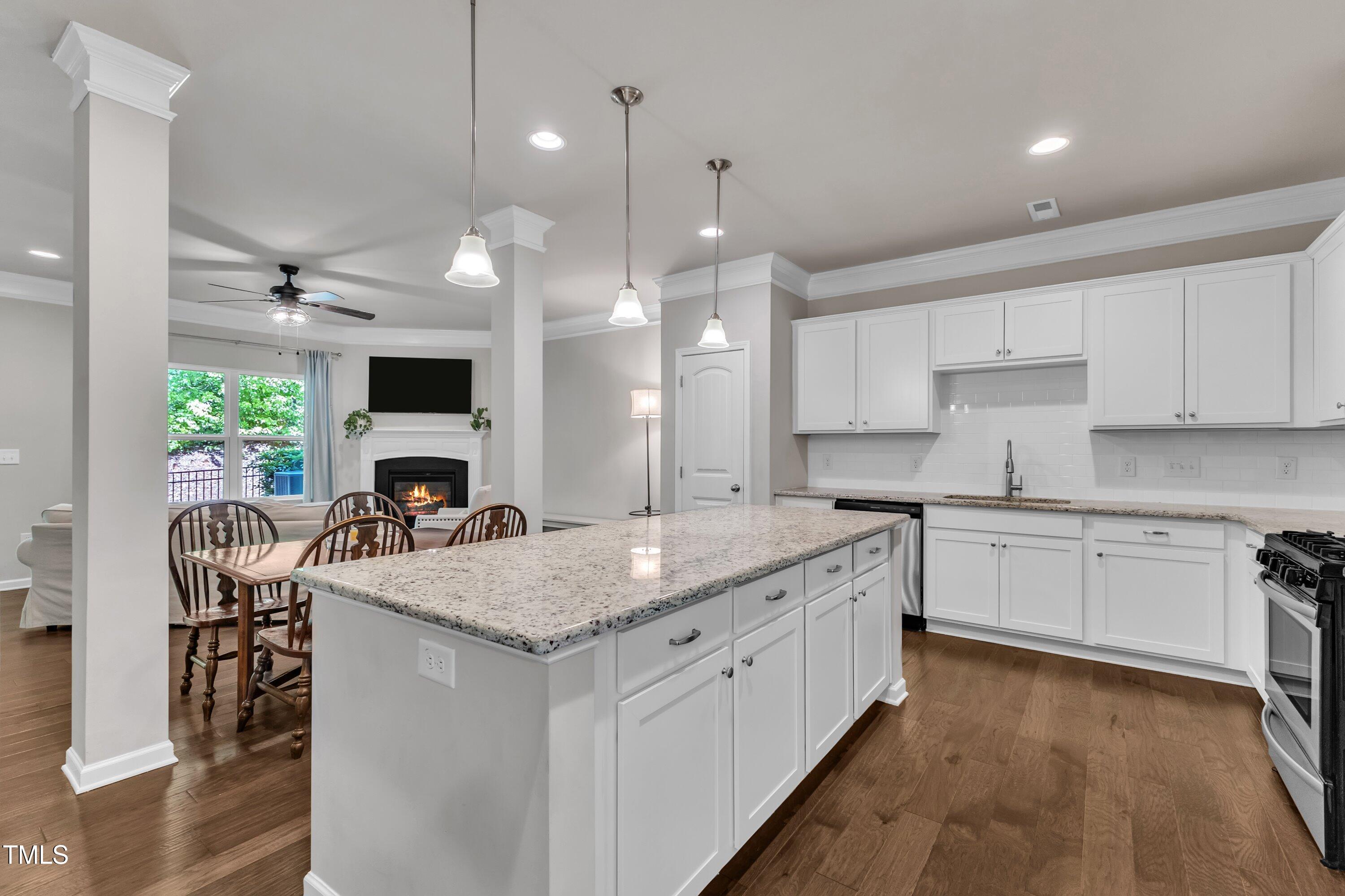 1230 Wingstem Place Raleigh, NC 27607 - Photo 9 of 41 a kitchen with kitchen island granite countertop a stove a sink a oven and a dining table with wooden floor