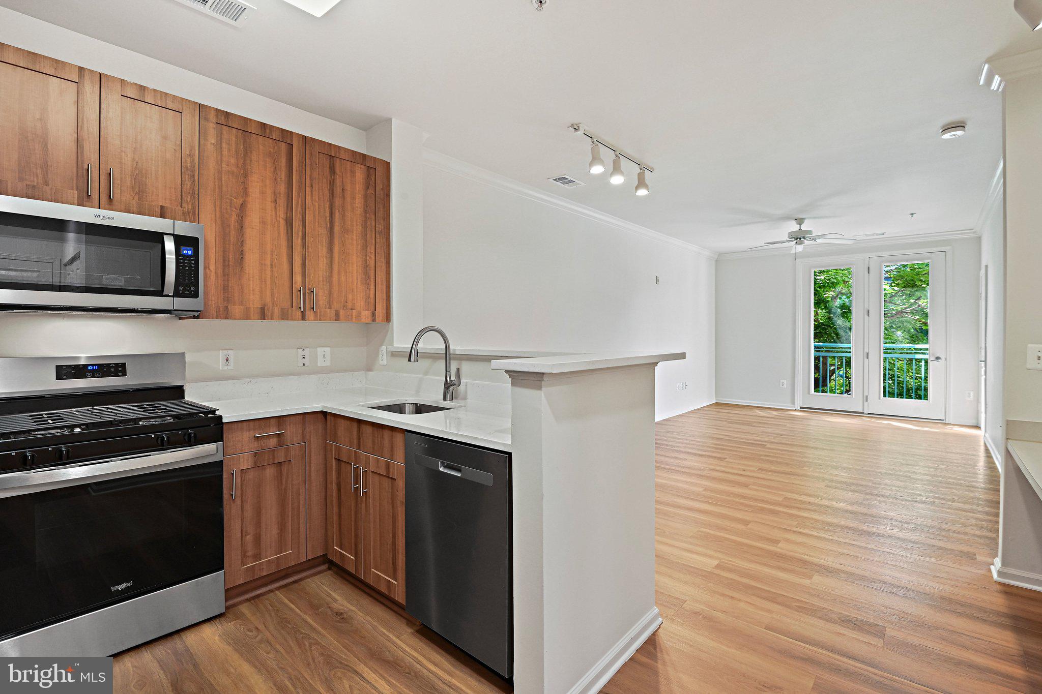 12001 Market Street, Unit 151 Reston, VA 20190 - Photo 3 of 25 a kitchen with granite countertop wooden cabinets stainless steel appliances and a window