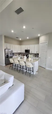 a living room with stainless steel appliances furniture and kitchen view