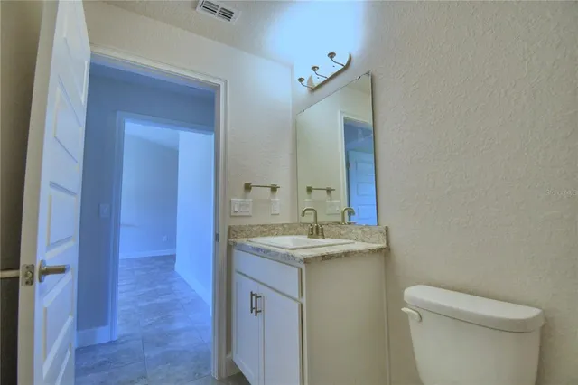 a bathroom with a granite countertop sink a toilet and a mirror