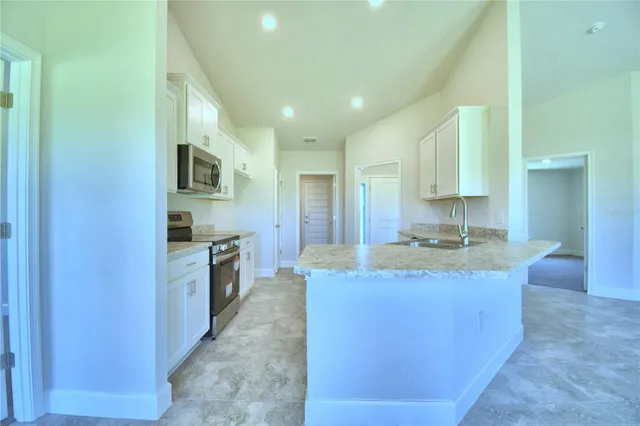 a large kitchen with stainless steel appliances granite countertop a stove a sink and a refrigerator