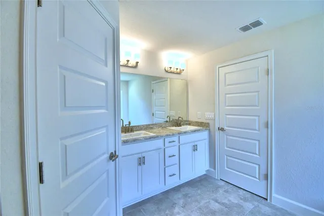 a bathroom with a granite countertop sink two mirror and a