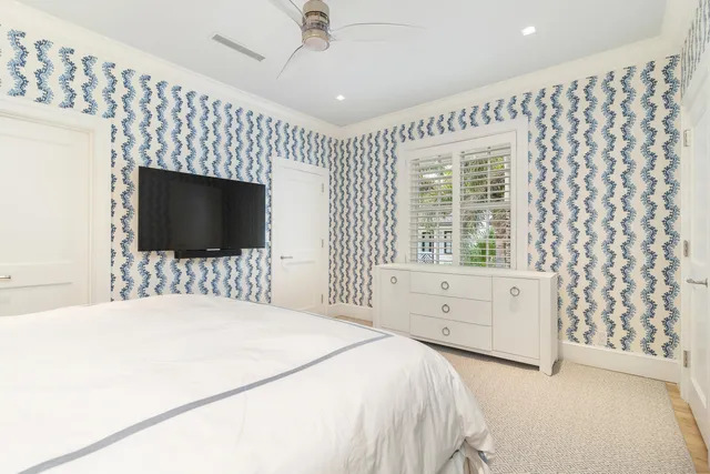 a bedroom with a large bed and a flat tv screen on dresser