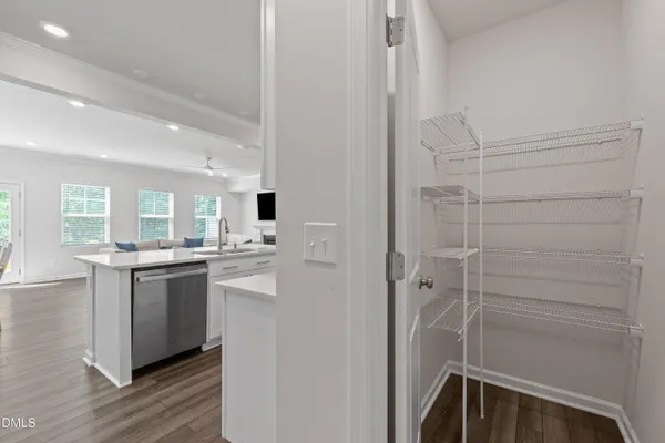 a large kitchen with kitchen island a sink dishwasher a stove and white cabinets with wooden floor