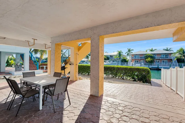 a view of a patio with a dining table and chairs with wooden floor and fence