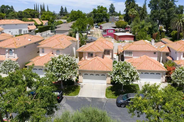 an aerial view of residential houses with outdoor space and trees