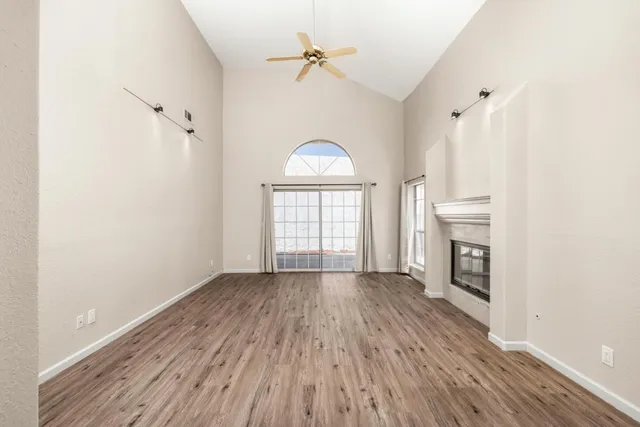 an empty room with windows a fireplace and wooden floor