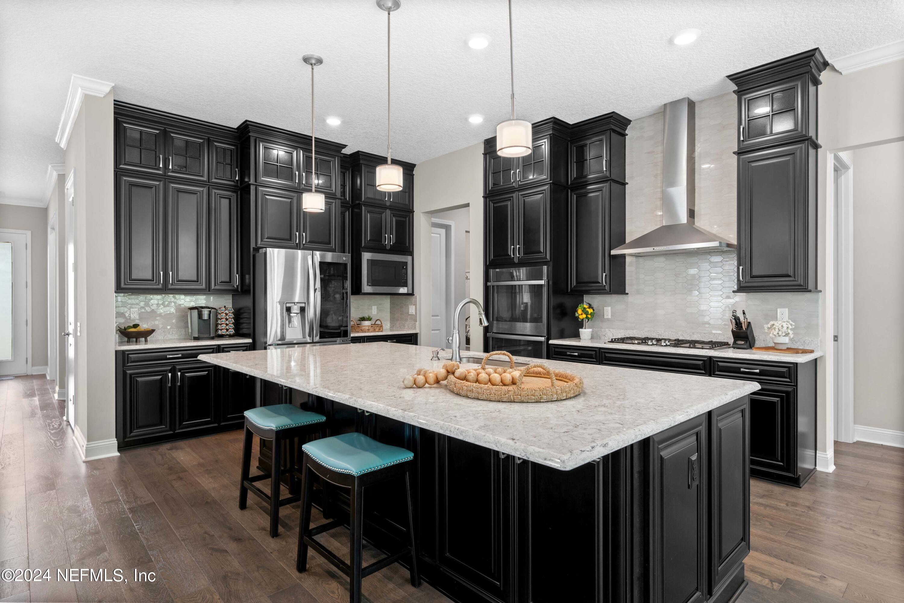 1924 Holmes Circle Fleming Island, FL 32003 - Photo 7 of 58 a kitchen with stainless steel appliances granite countertop a stove a refrigerator and a dining table with wooden floor