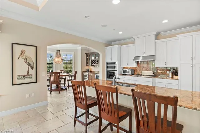 a kitchen with stainless steel appliances granite countertop a stove a sink a microwave a island with a dining table and chairs