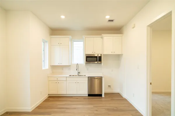 a view of kitchen with stainless steel appliances a sink and wooden floor