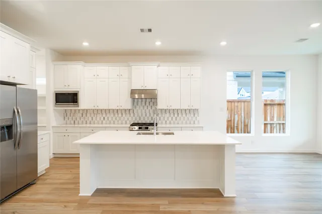 a room with kitchen island stainless steel appliances wooden floor and window