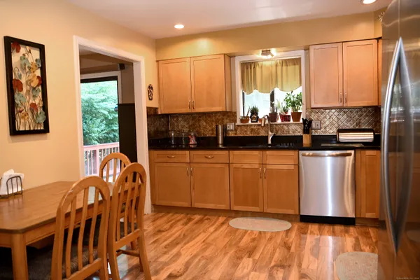 a kitchen with stainless steel appliances granite countertop a stove top oven a sink a dining table and chairs