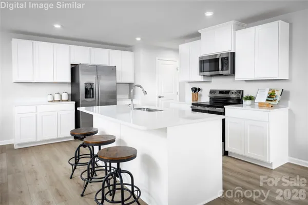 a kitchen with stainless steel appliances a microwave a stove a sink a refrigerator and cabinets