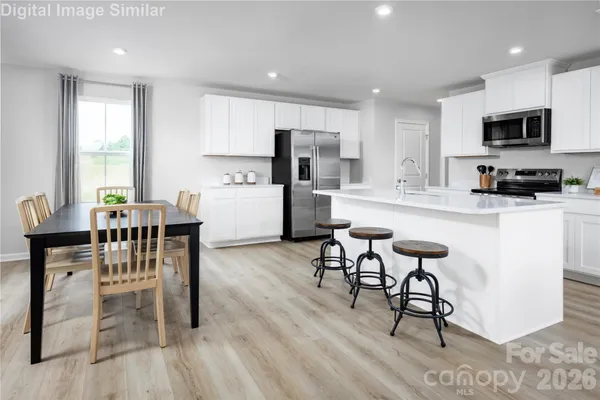 a kitchen with stainless steel appliances kitchen island granite countertop a table chairs and a refrigerator