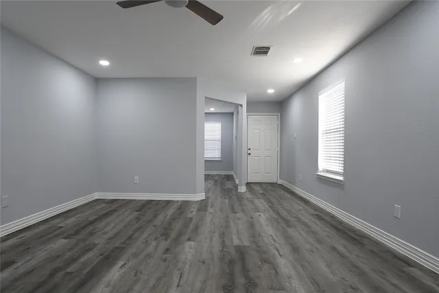 an empty room with wooden floor and windows