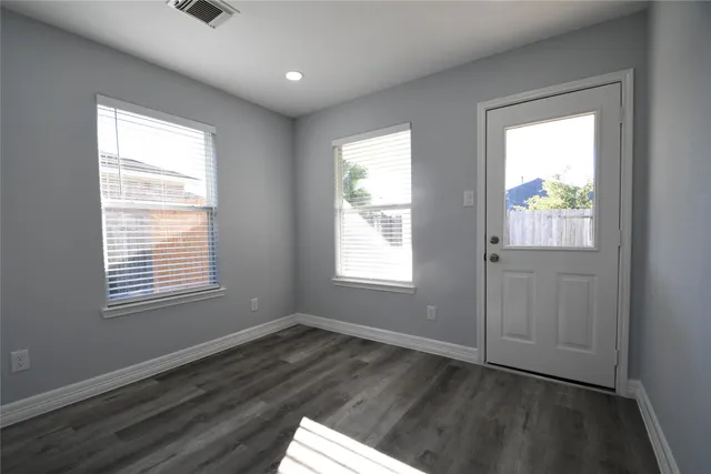 a view of an empty room with wooden floor and a window