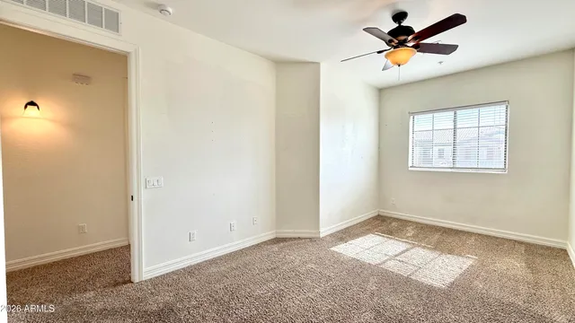 an empty room with a window and a ceiling fan