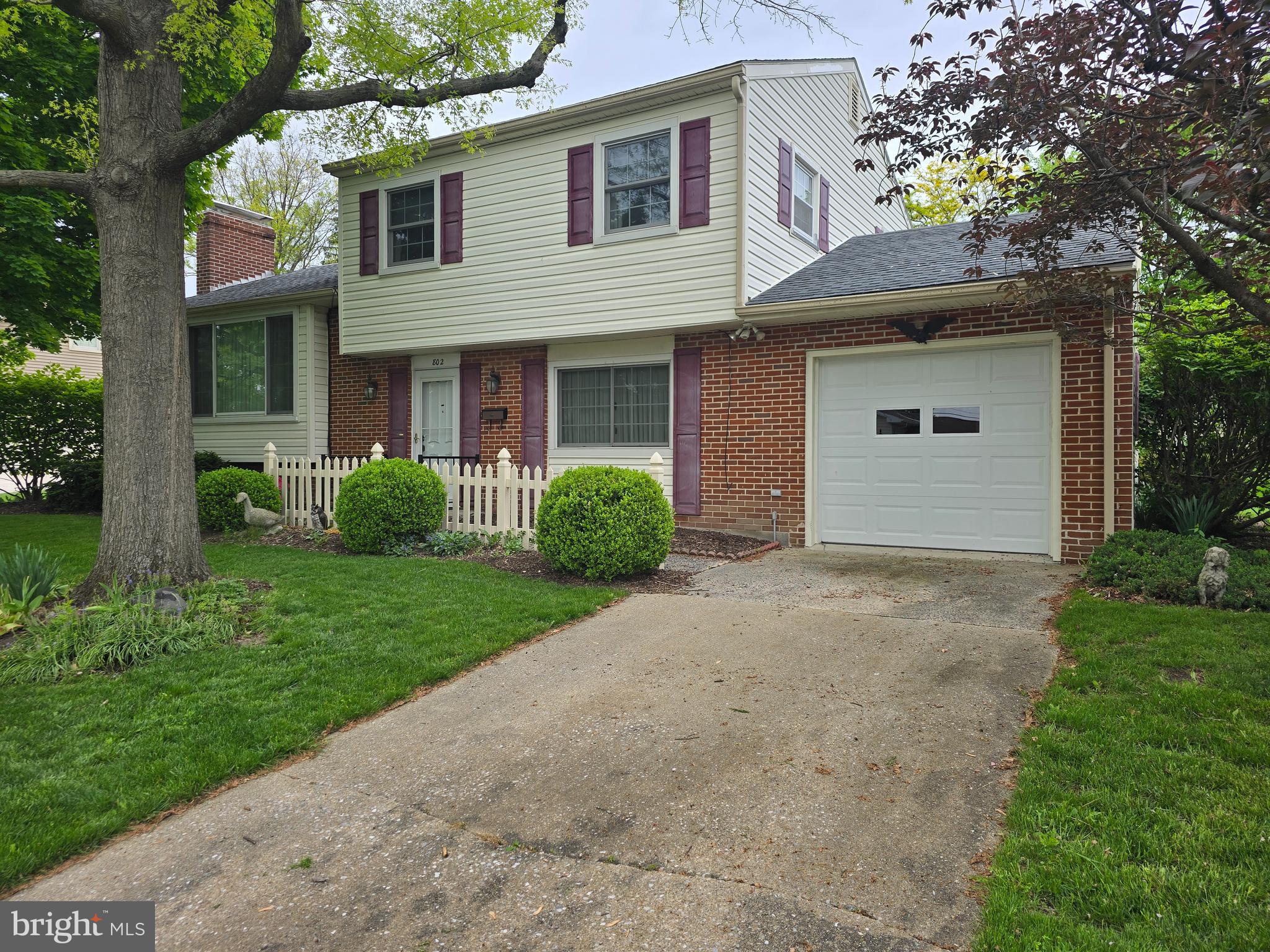 a view of a house with a yard and a large tree