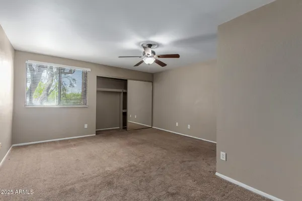 a view of an empty room with a ceiling fan and window