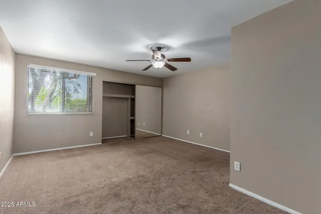 a view of an empty room with a ceiling fan and window
