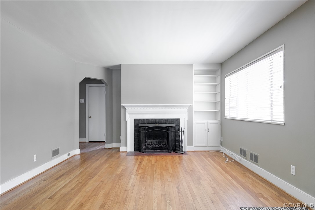 3911 Arklow Road Richmond, VA 23235 - Photo 5 of 39 an empty room with wooden floor fireplace and windows