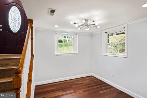 an empty room with wooden floor a ceiling fan and windows