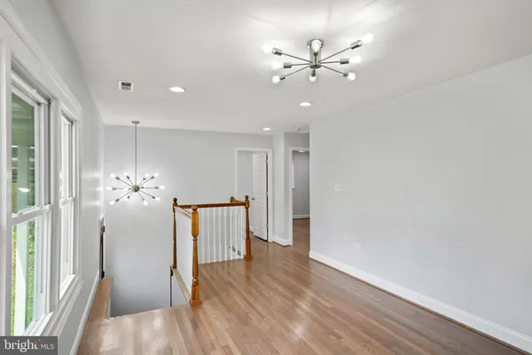 a view of a livingroom with a chandelier fan and wooden floor