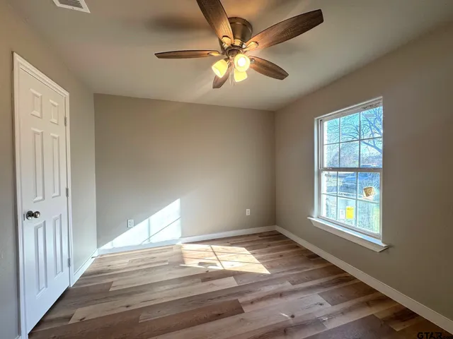 a view of empty room with wooden floor and fan