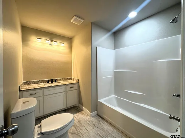 a bathroom with a granite countertop toilet a sink and bathtub