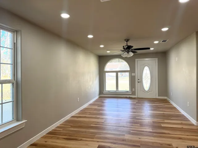 an empty room with wooden floor and windows