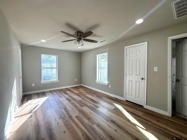 a view of an empty room with a window and wooden floor