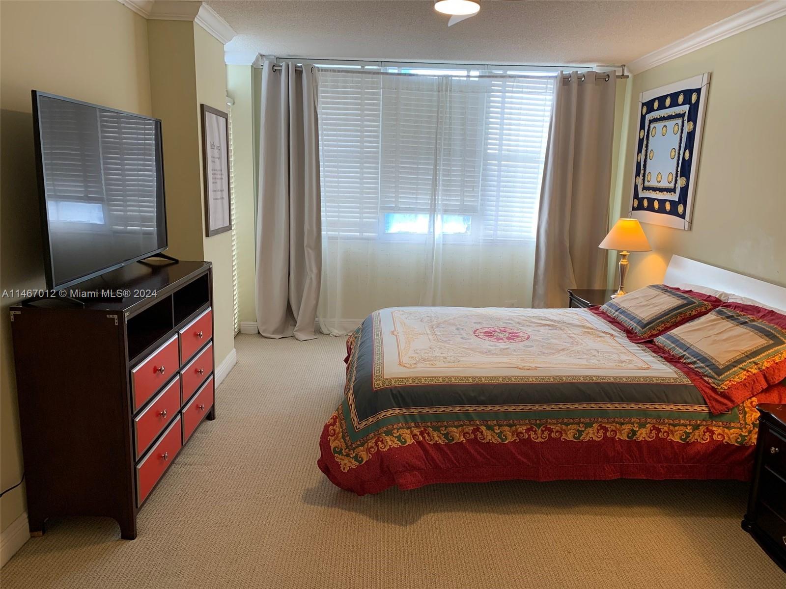 6039 Collins Avenue, Unit 1630 Miami Beach, FL 33140 - Photo 11 of 37 a bedroom with a bed and dresser with window