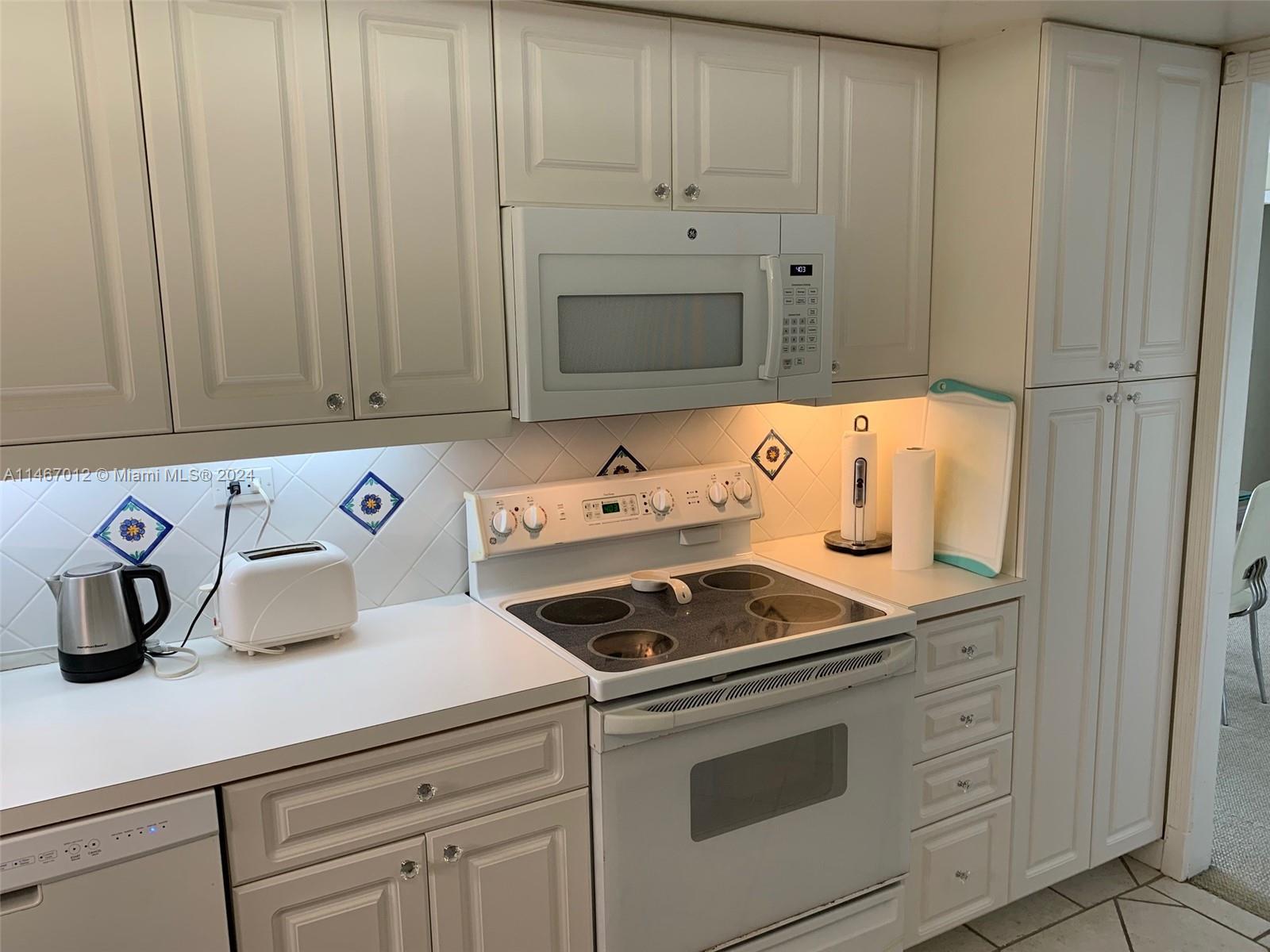 6039 Collins Avenue, Unit 1630 Miami Beach, FL 33140 - Photo 3 of 37 a kitchen with granite countertop cabinets and white appliances