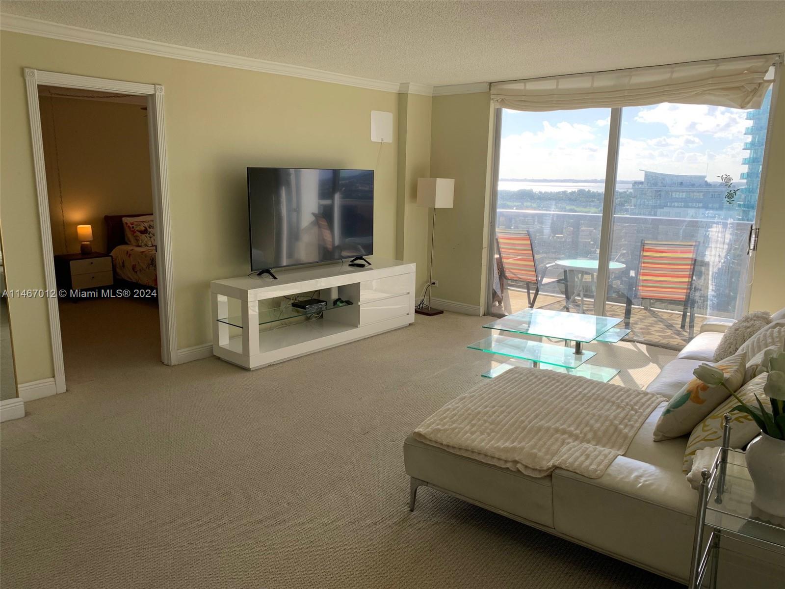 6039 Collins Avenue, Unit 1630 Miami Beach, FL 33140 - Photo 8 of 37 a living room with furniture and a flat screen tv