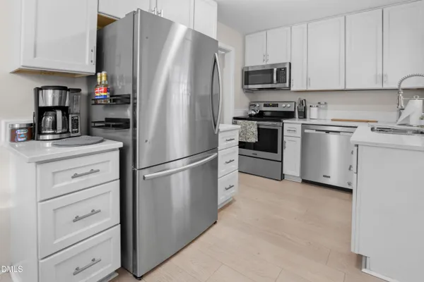 a kitchen with stainless steel appliances white cabinets and a refrigerator