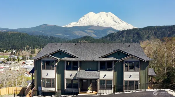 a front view of a house with a yard and mountain view in back
